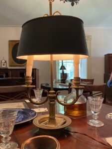 Located in the Game room at the Mount Vernon Hotel, this recent acquisition Bouillotte Lamp is currently illuminating an array of cards and small cut glasses. As one can see the metal shade reflects light exclusively downwards and onto the table. 
